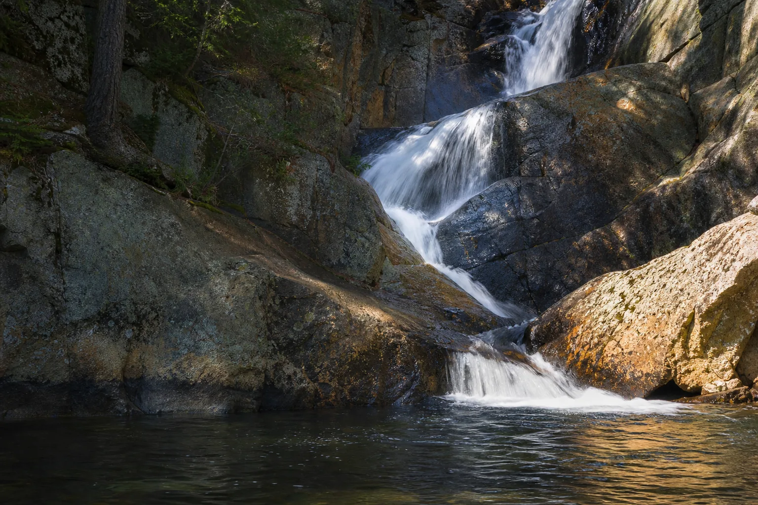 Close detail of Smalls Falls water sliding across iron-stained metamorphic bedrock with quartz veining