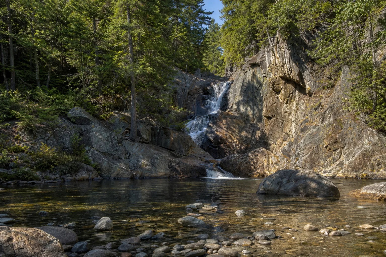 Smalls Falls wide view down the sandy stream gorge with the upper tiers visible from the footbridge
