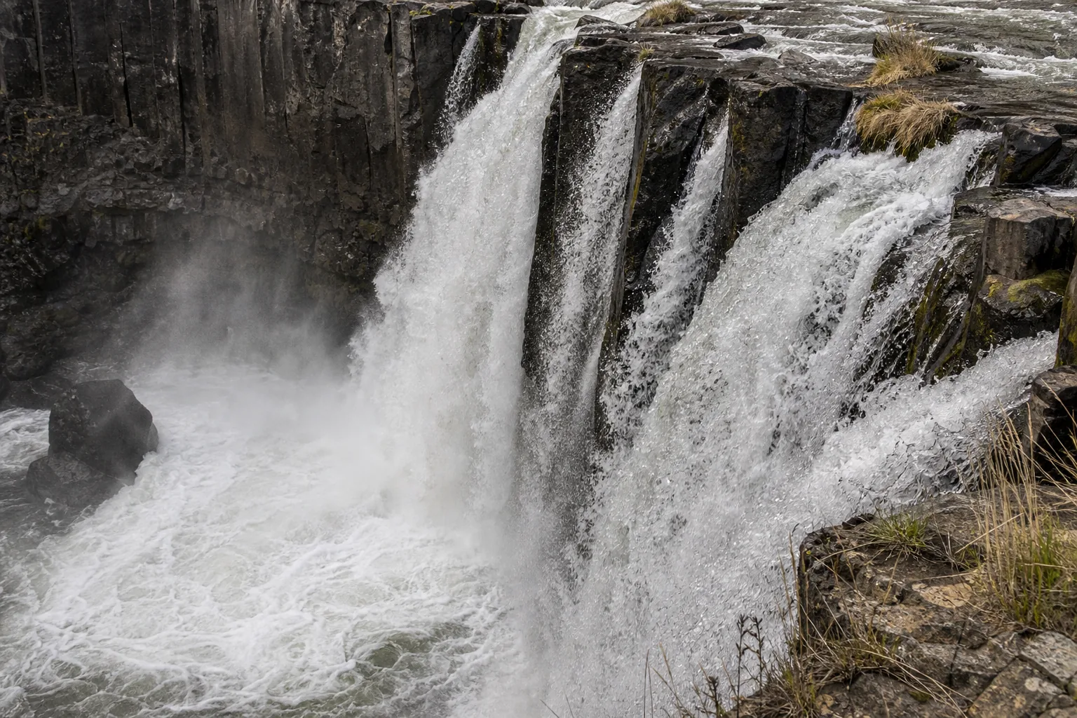 Detail of White River Falls showing pale glacial-flour water sliding across dark Columbia River Basalt columns